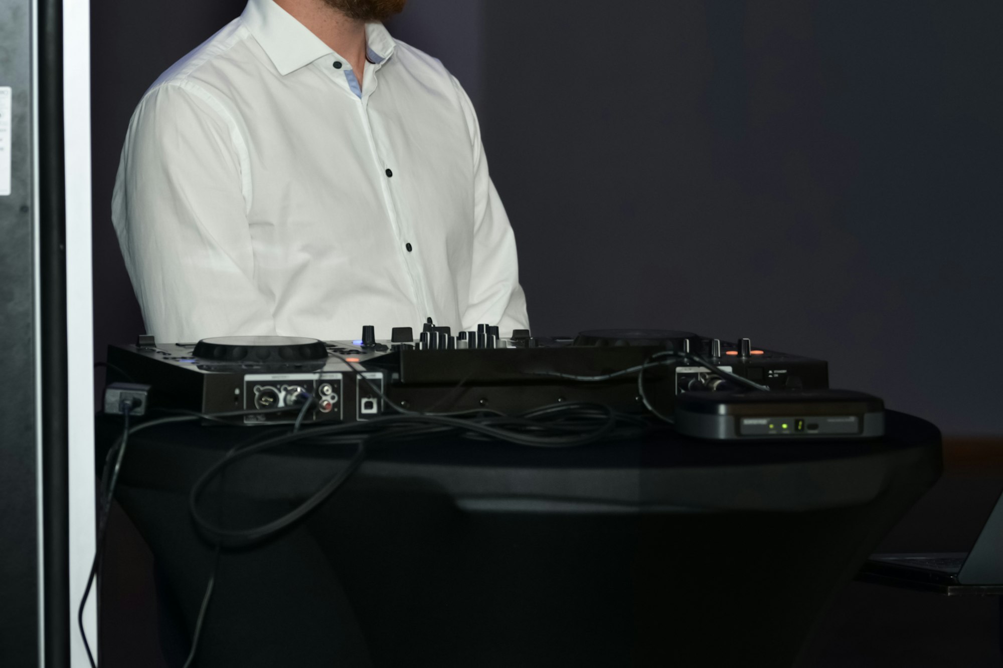 A DJ in a white shirt and his equipment at a wedding