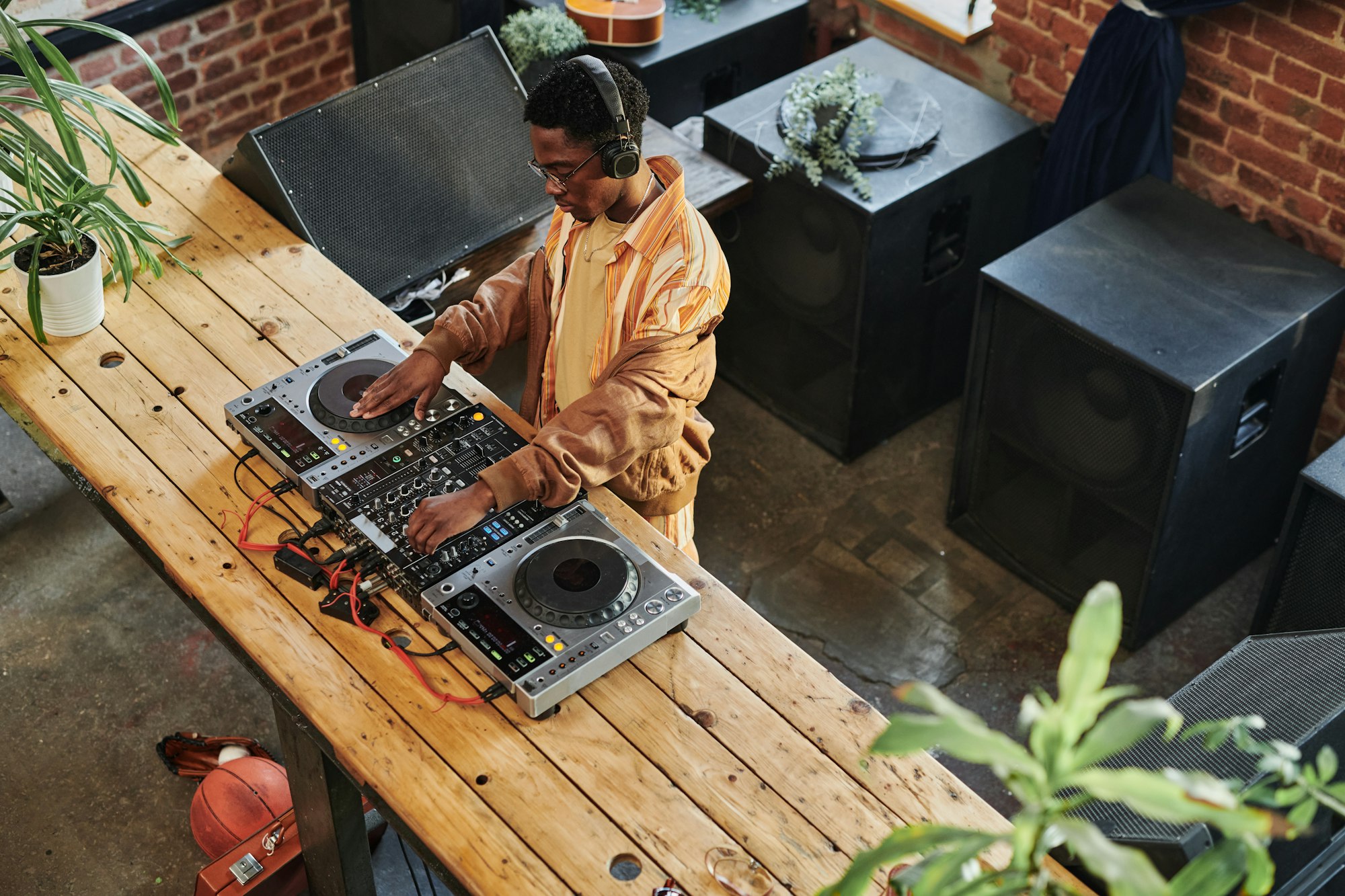 Overview of young African American male deejay standing by dj set